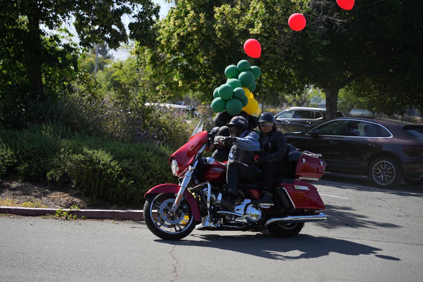 Rider and passenger on a red Harley rolling out under the pan-African balloon arch at staging, 2025 Freedom Ride